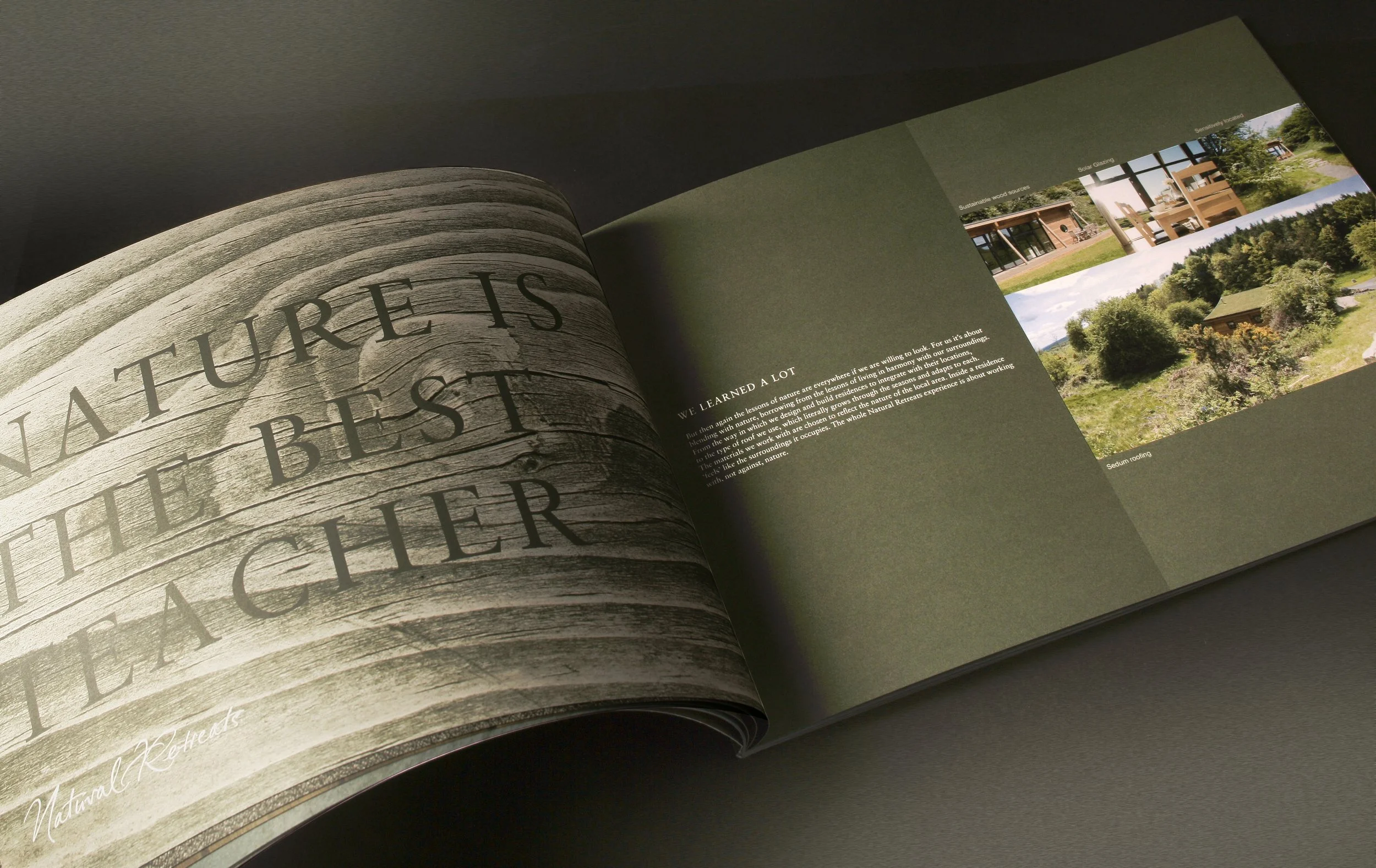 An open magazine showing a large wooden sign with the words "Nature is the best outdoors" printed on it, with text and images of outdoor scenes and houses on the adjacent page.