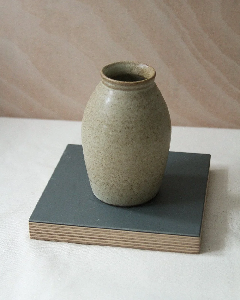 A round bellied bud vase in a sandy glaze