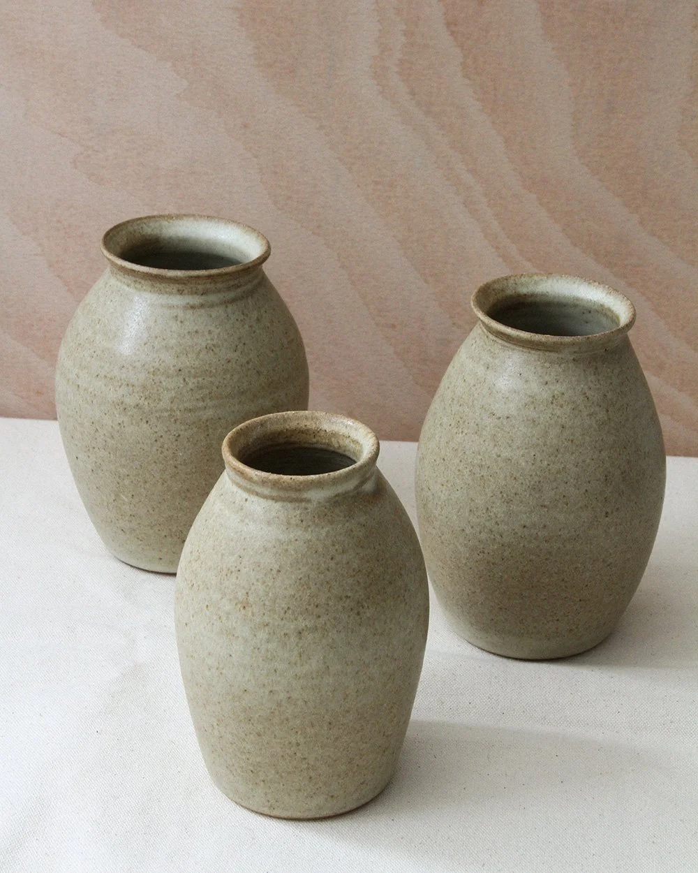 Three round bellied bud vases in a sandy glaze
