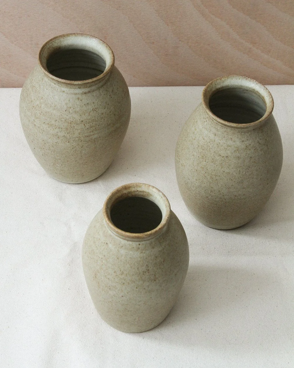 Three round bellied bud vases in a sandy glaze viewed from above