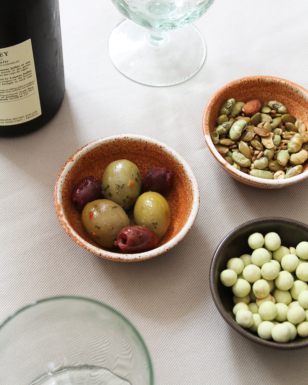 A table scene showing the little bowls in use, housing olives and wasabi peas and seeds.