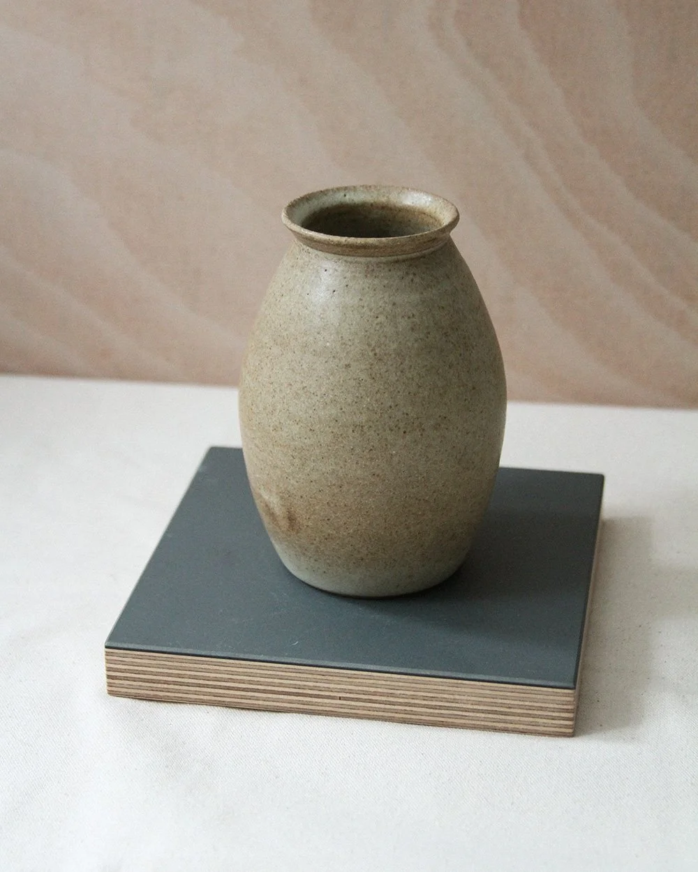 A round bellied bud vase in a sandy glaze