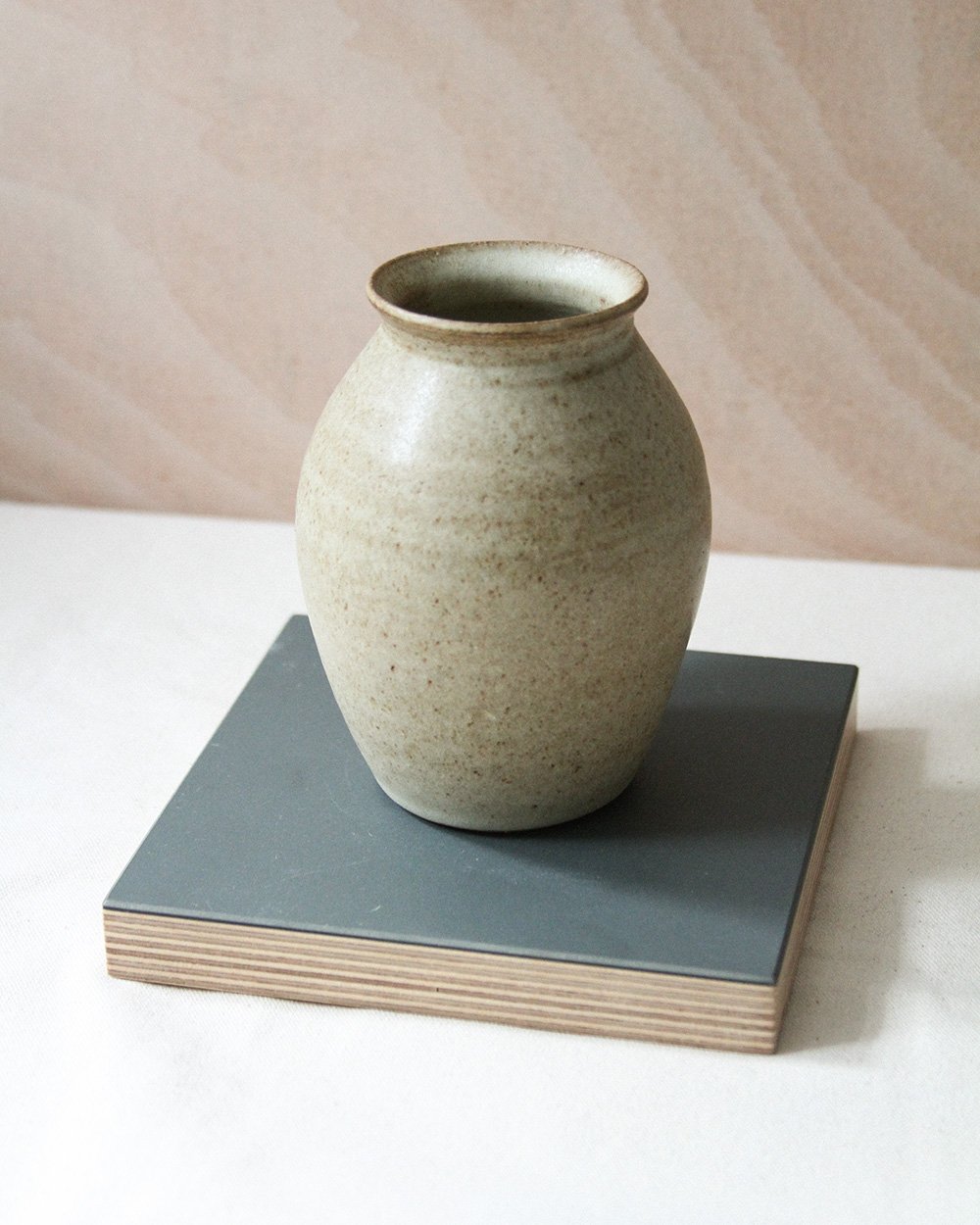 A round bellied bud vase in a sandy glaze