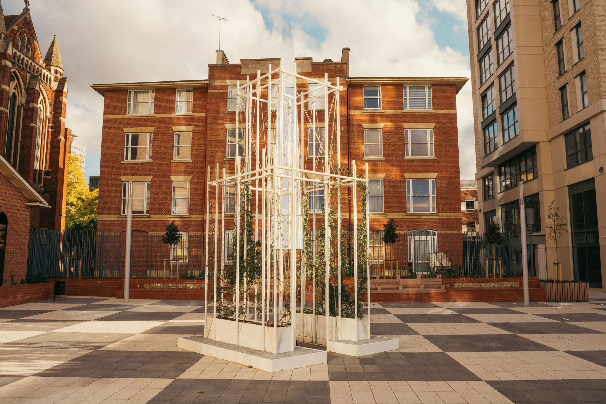 An outdoor plaza with a modern white sculpture and buildings in the background.