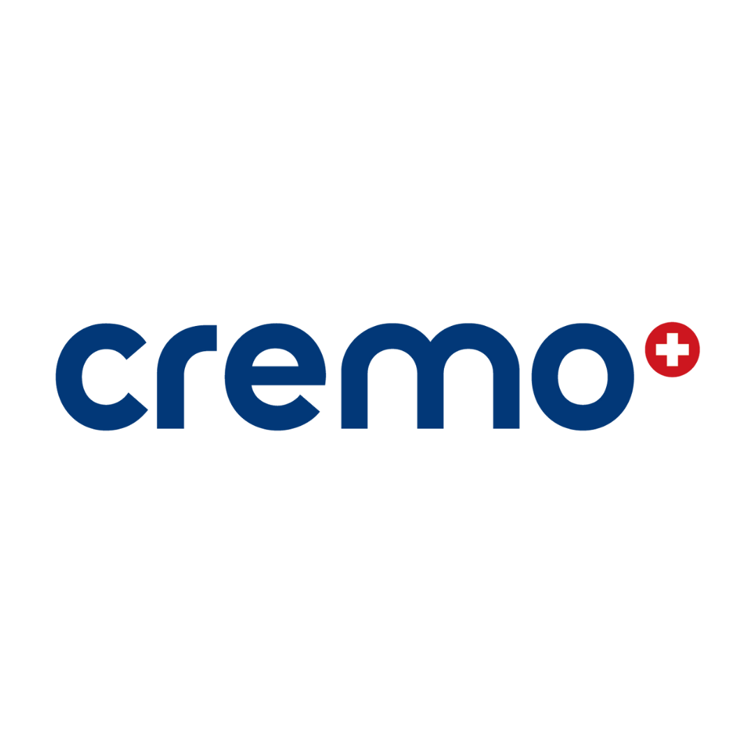 Logo der Marke 'Cremo', bestehend aus dem Schriftzug 'cremo' in blauer Schrift mit einem roten Kreis mit weißem Kreuz auf der rechten Seite. Das Logo hat einen schwarzen Hintergrund.