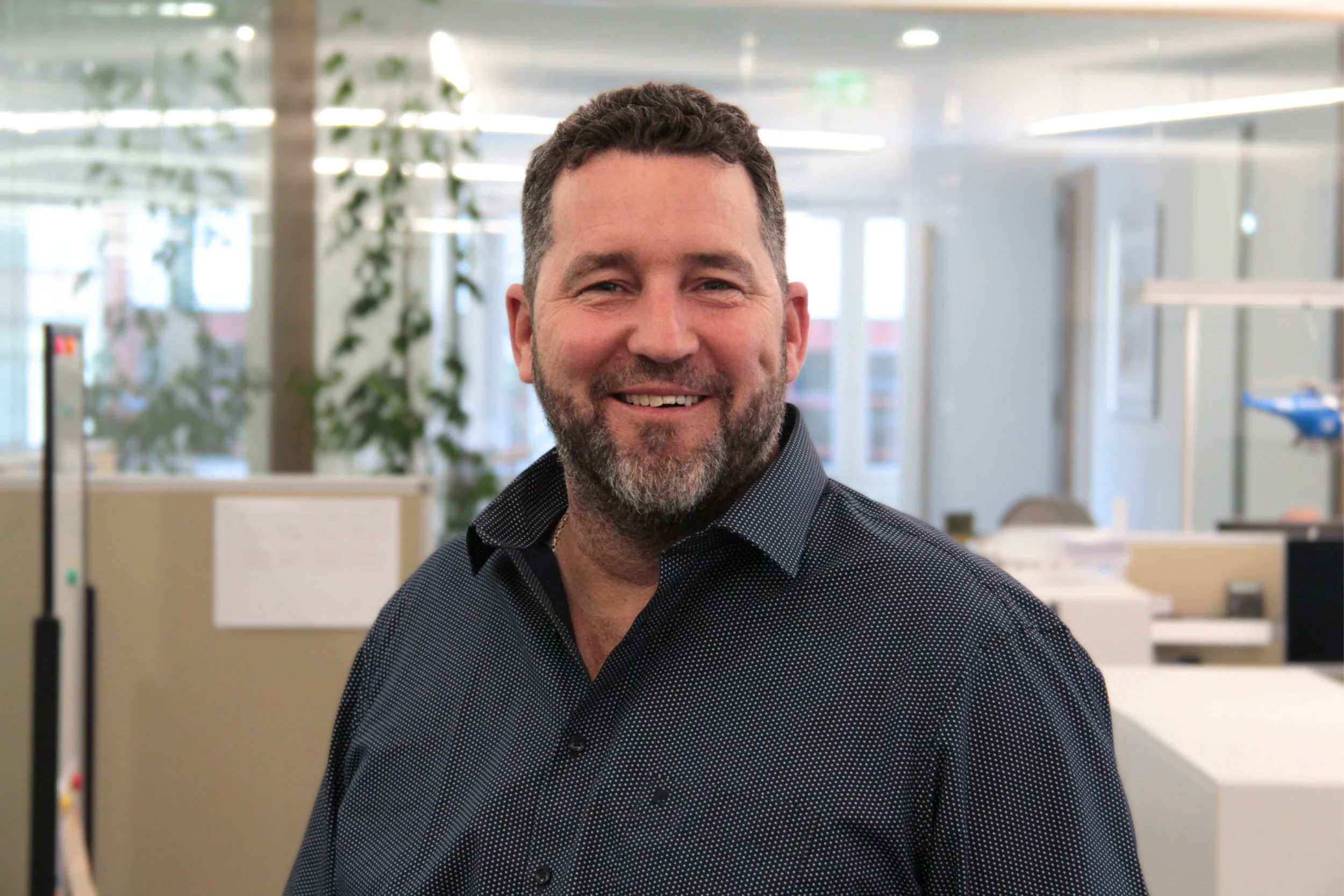 Lächelnder Mann mit Bart in einem modernen Büro.