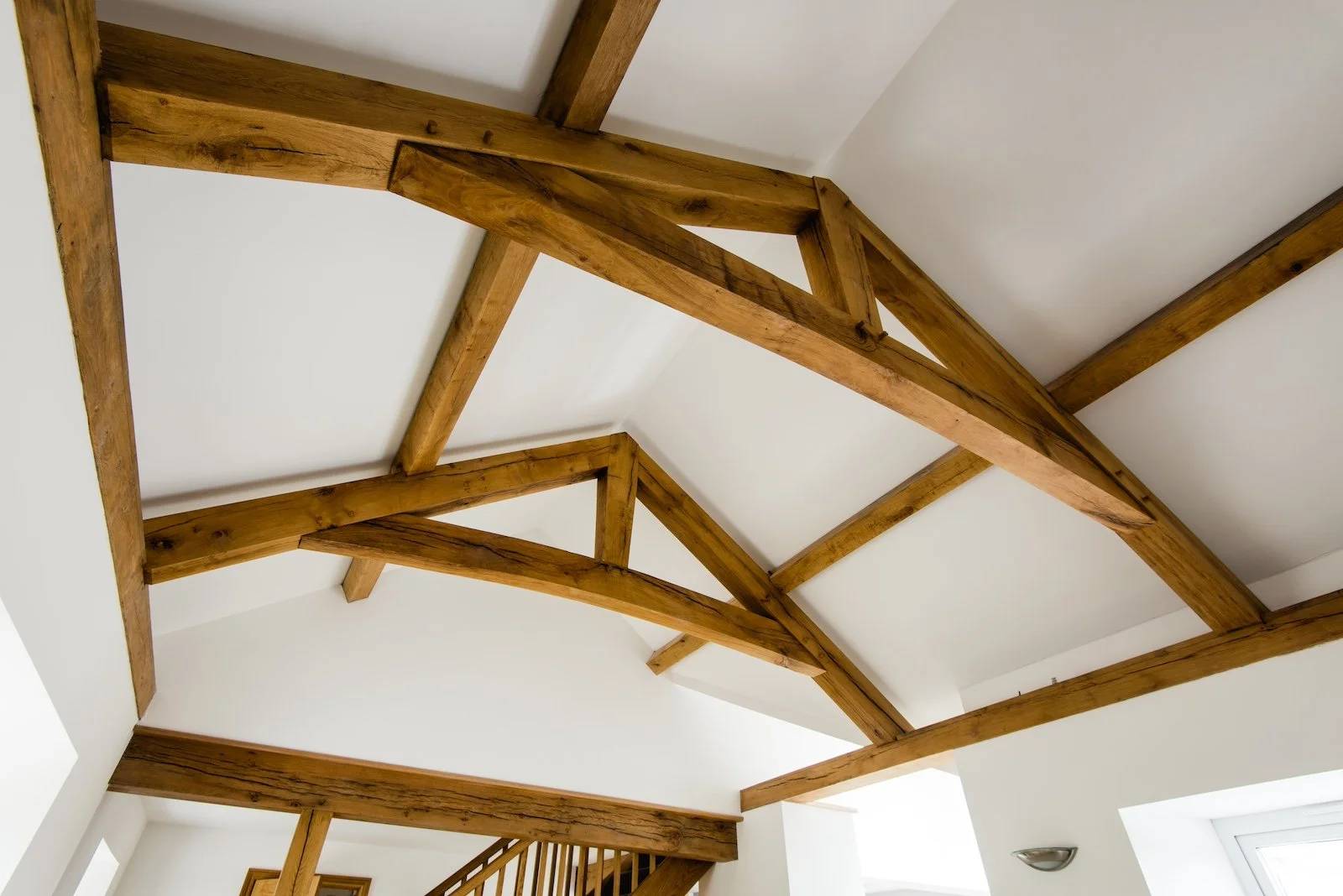 Interior view of a ceiling featuring exposed wooden beams and trusses in a residential space.
