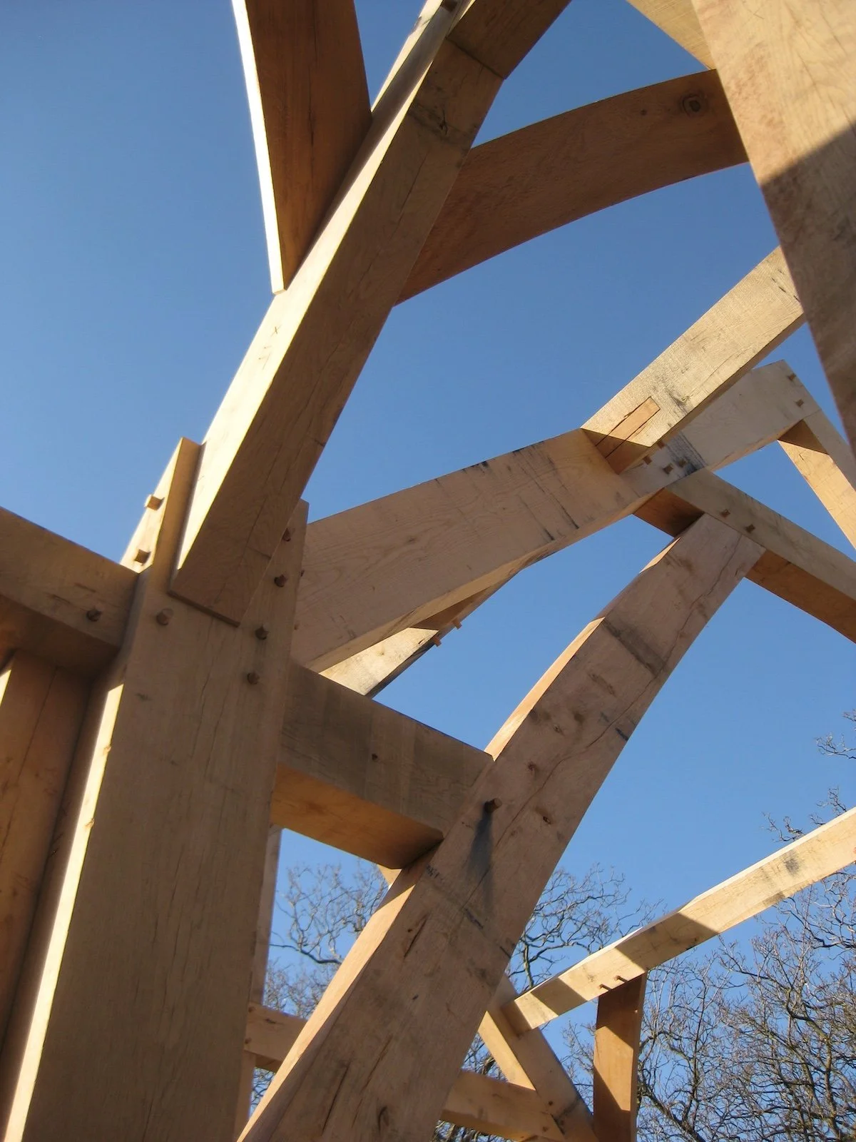 Wooden framing structure under construction against a clear blue sky.