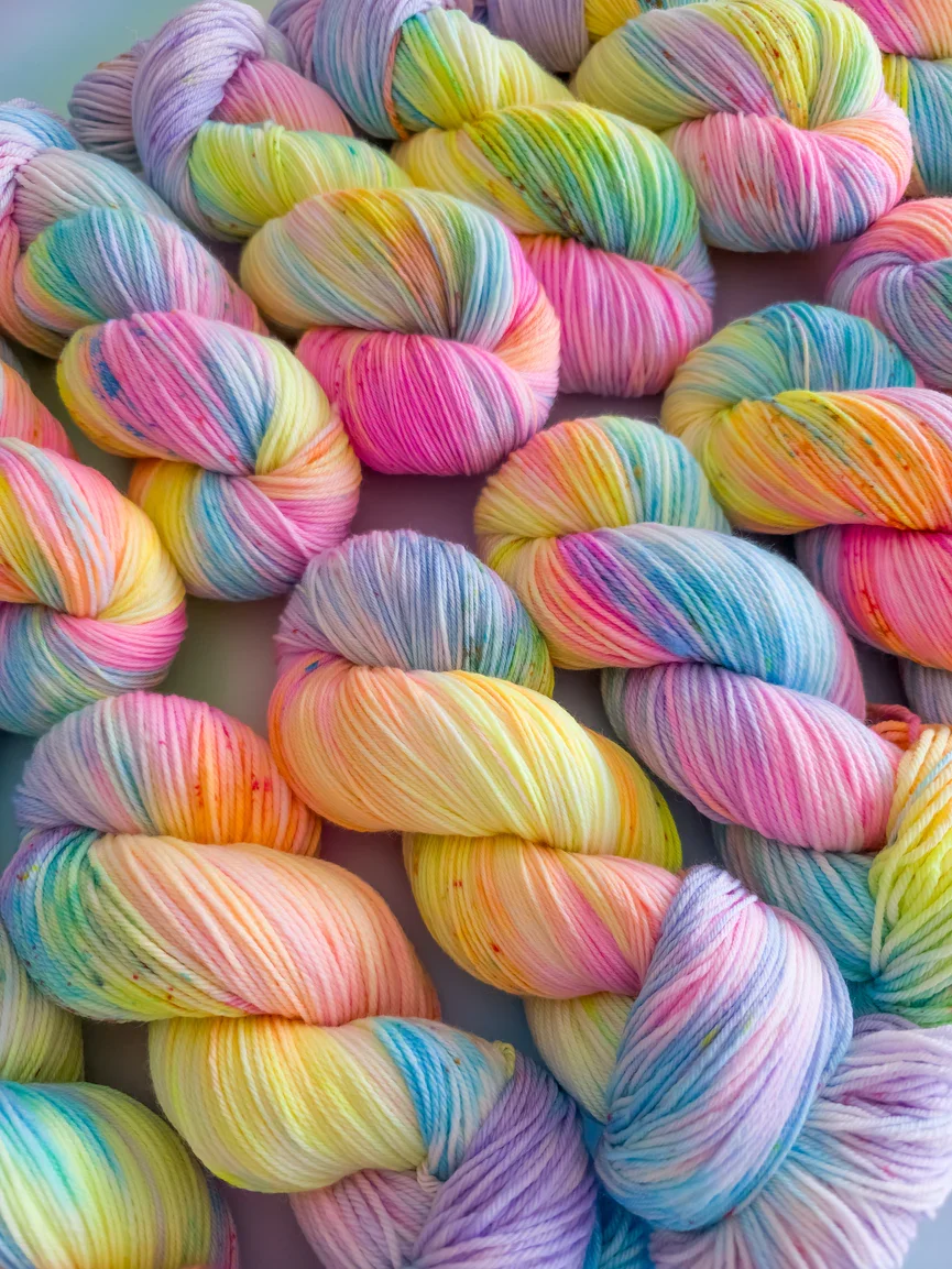 Colorful twisted skeins of variegated yarn in pastel rainbow shades.