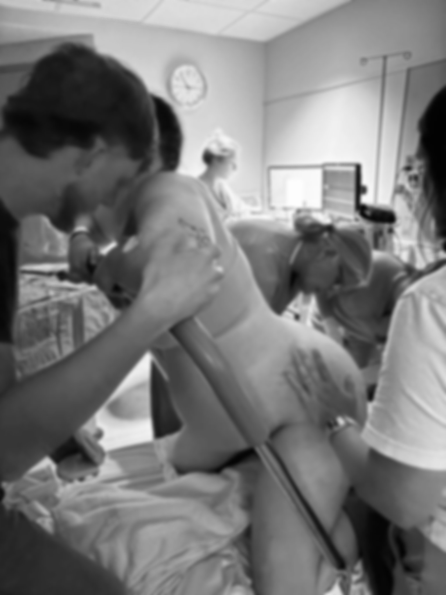 Medical team attending to a pregnant woman in a hospital delivery room.