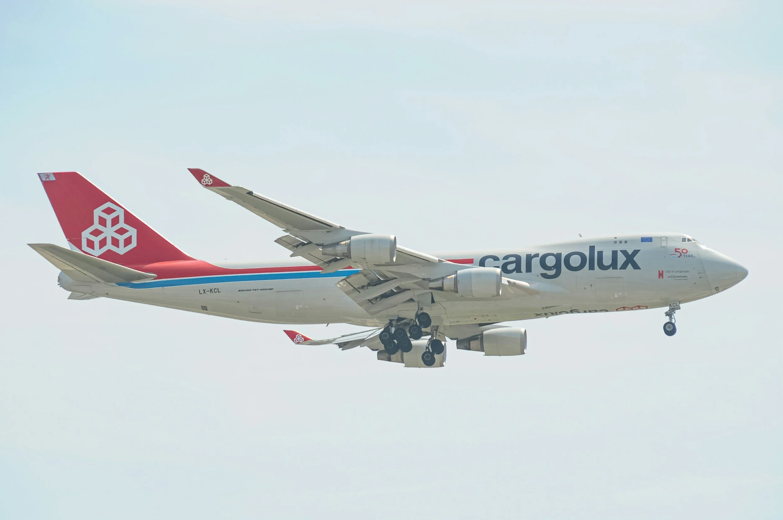 Workers loading a large crate onto an airplane using a baggage loader at an airport.