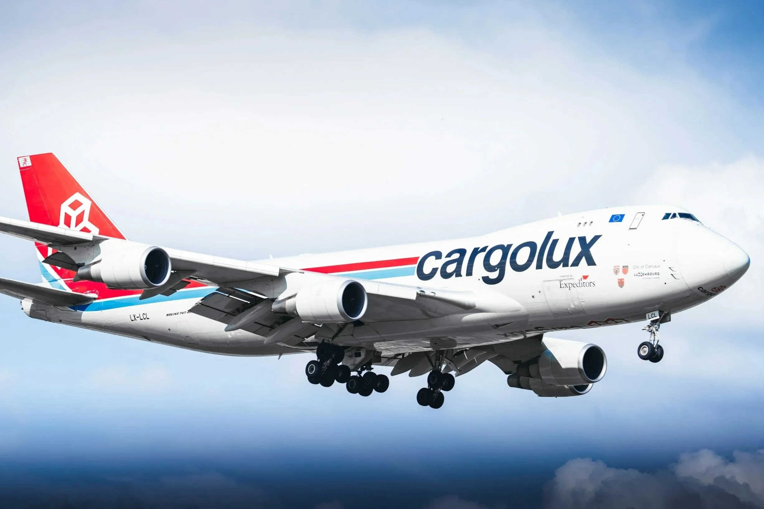 A large, retired Boeing 747 aircraft on the tarmac with a ground service vehicle and passenger boarding stairs nearby, under a blue sky.