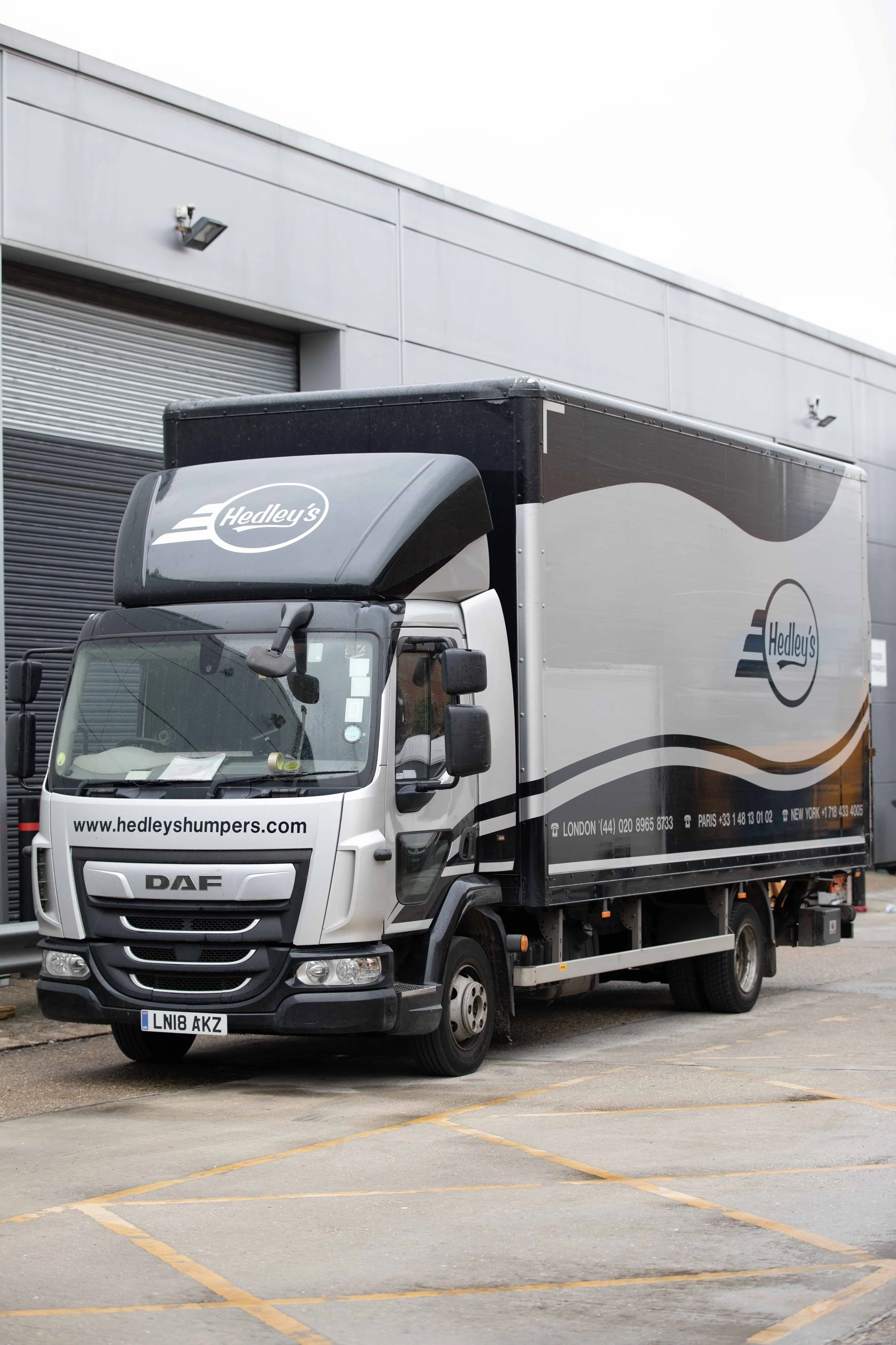 A delivery truck with Hedley's branding parked in a lot outside a warehouse.