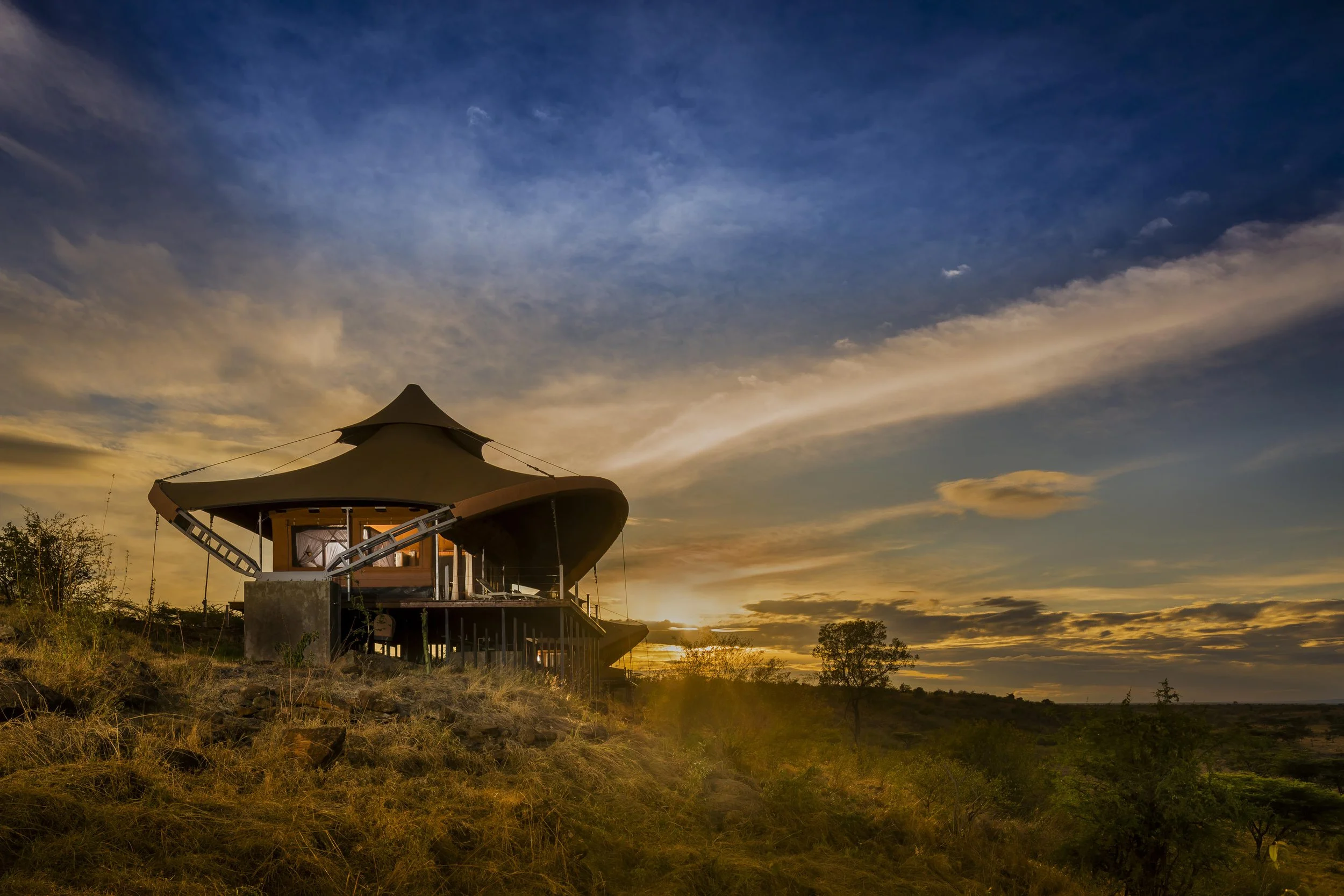 Treehouse on stilts in a landscape at sunset with a colorful sky and scattered clouds