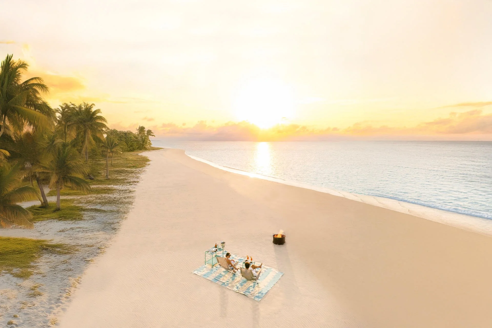 Relaxing on a beach at sunset with a picnic setup and campfire