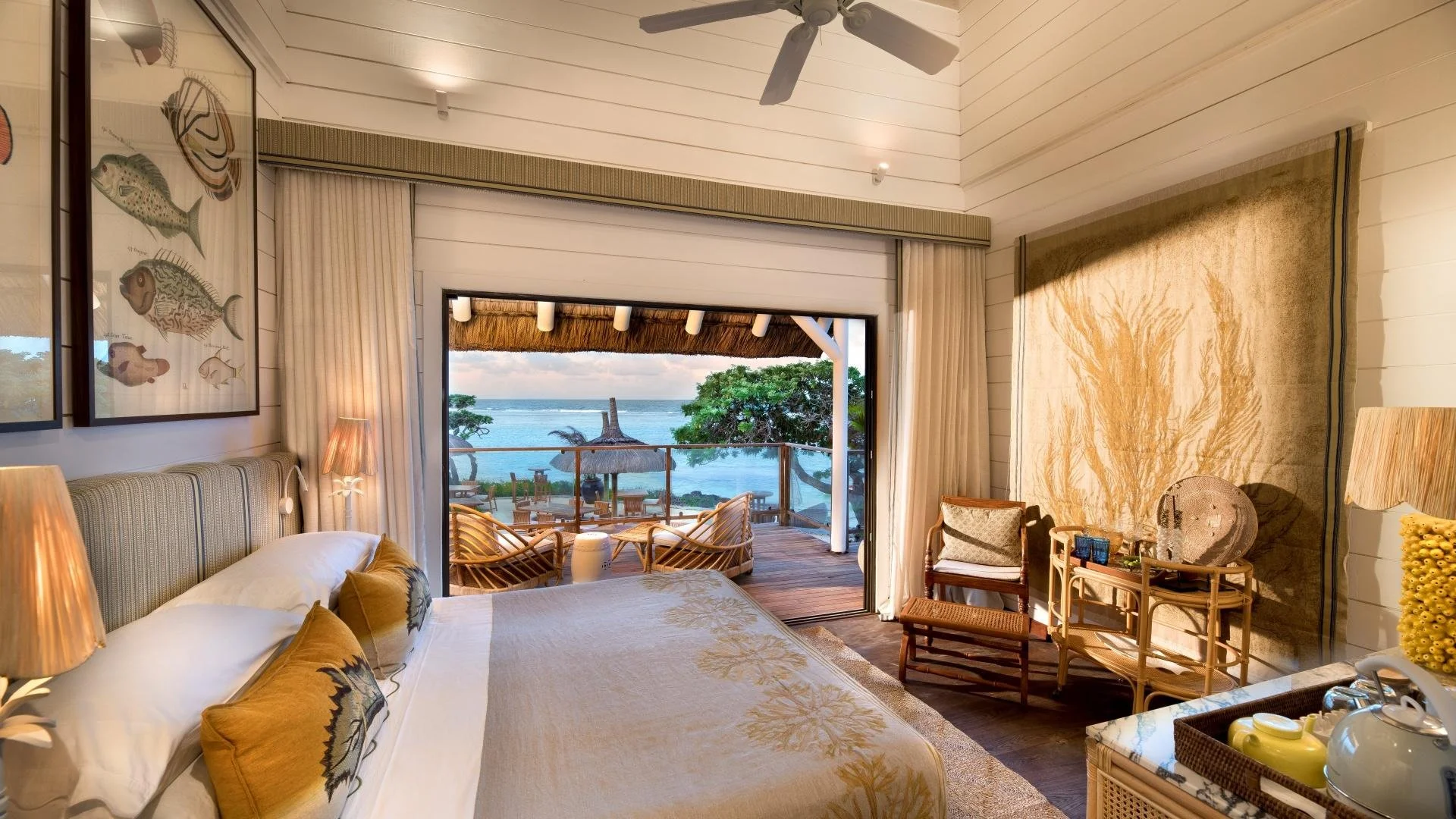 Beachfront hotel room with a large bed, ocean view, and balcony with seating area.