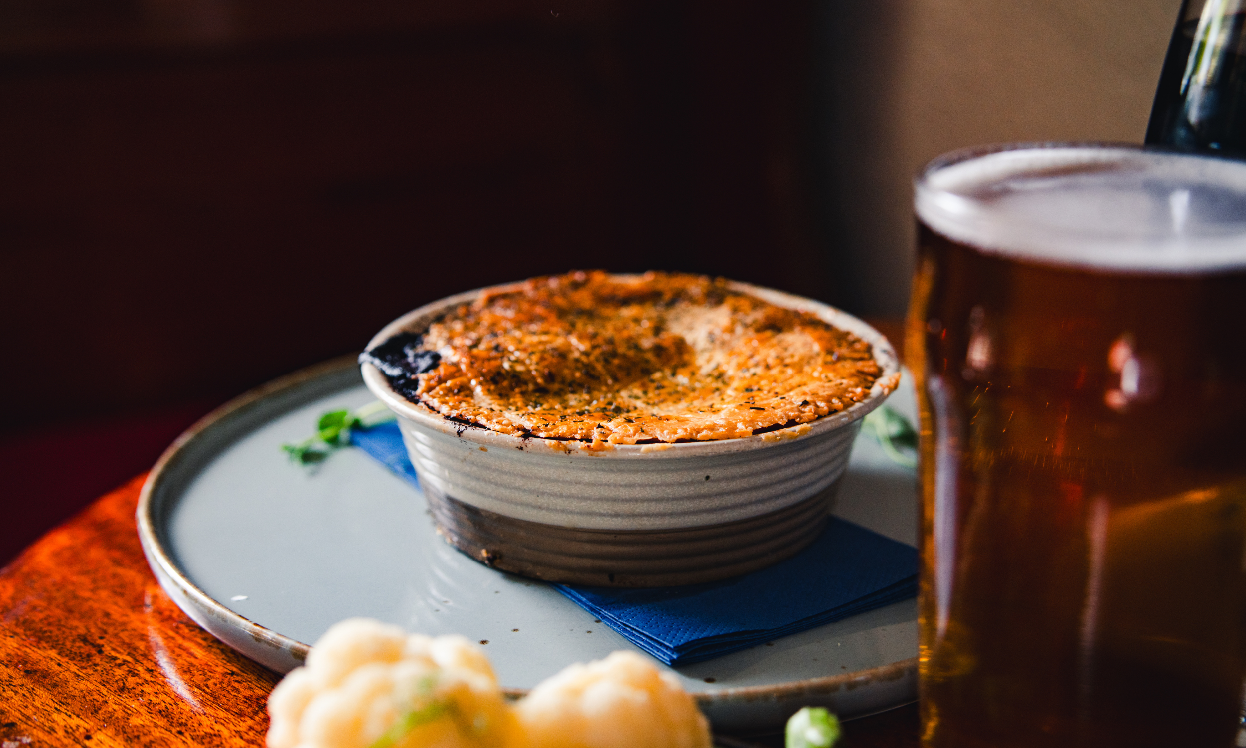 Welsh Dragon Pie at The Ship Inn, Red Wharf Bay. Our signature dish features mint & chilli slow braised local lamb with a Welsh cheesy mash topping and side vegetables. The perfect hearty comfort food right on the beach.