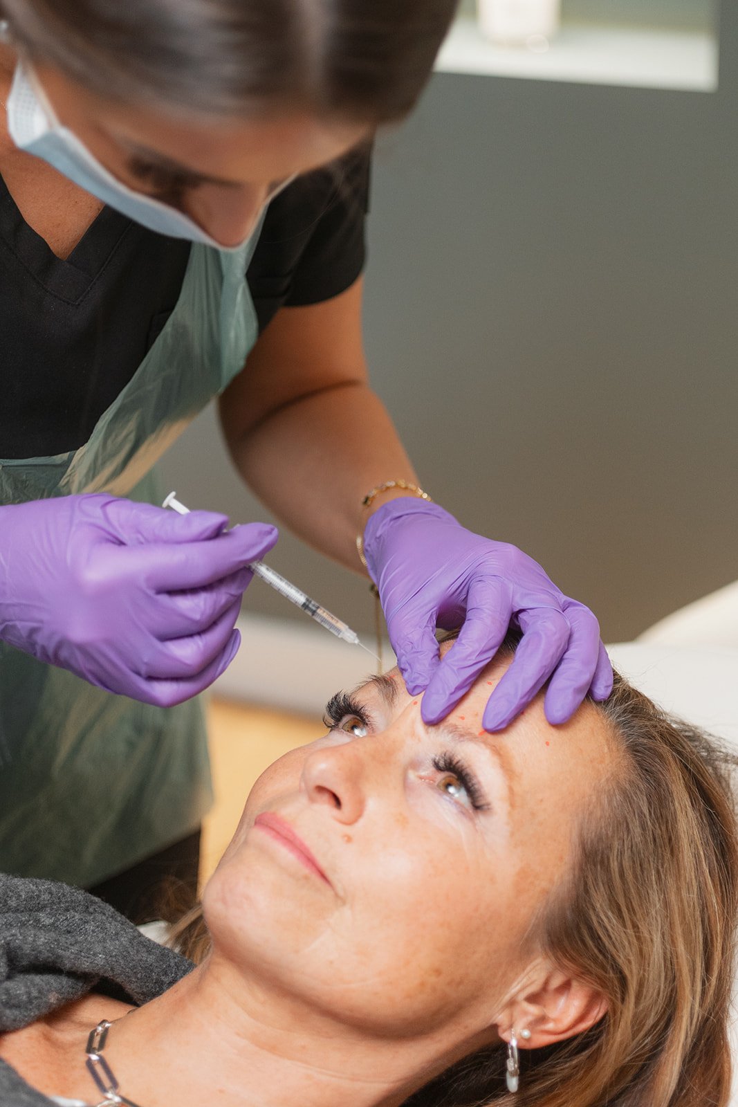 Clinician is using a syringe and needle to apply an anti-wrinkle treatment to women