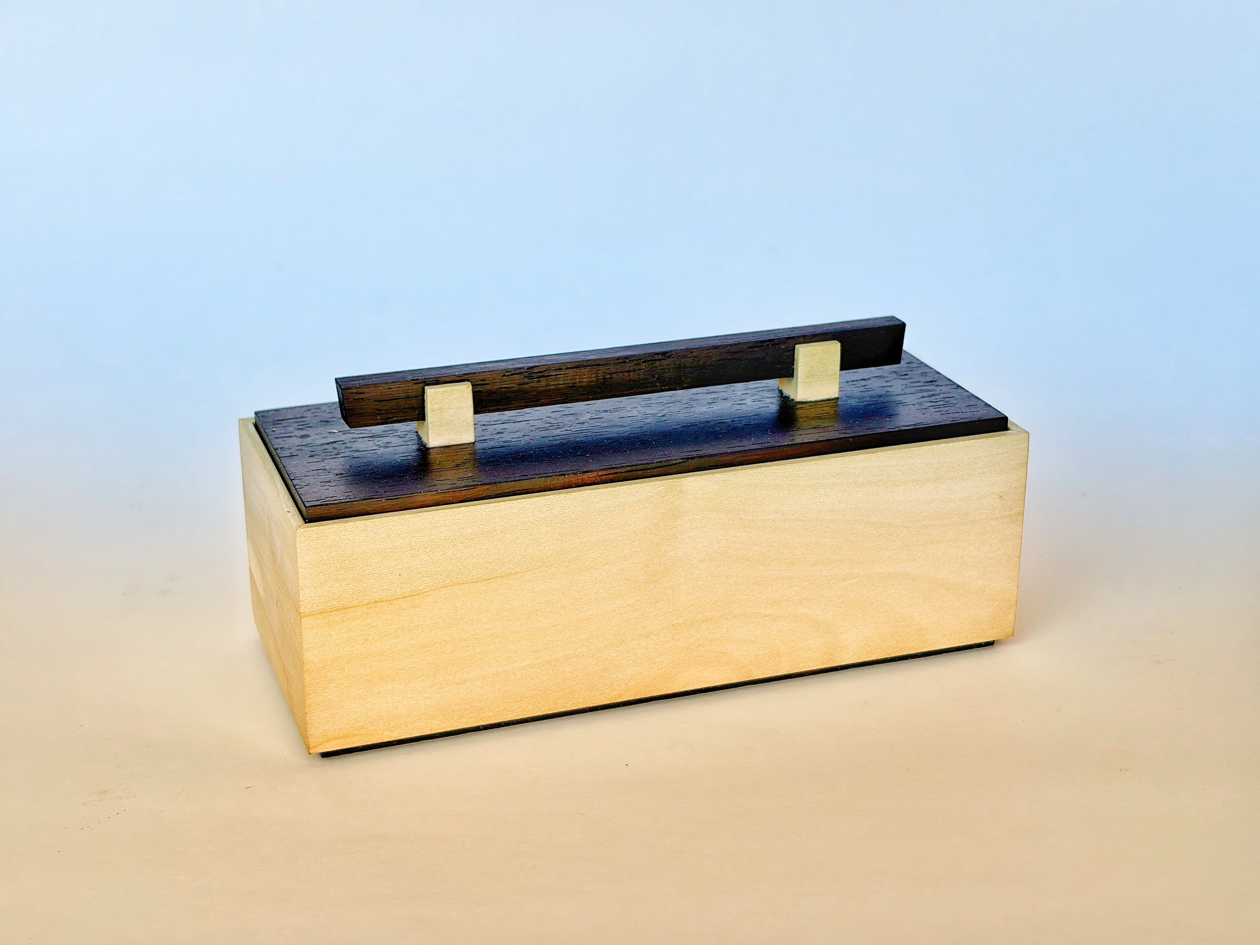 A wooden box with a dark wooden handle on top, supported by cream-colored supports, on a plain white background.