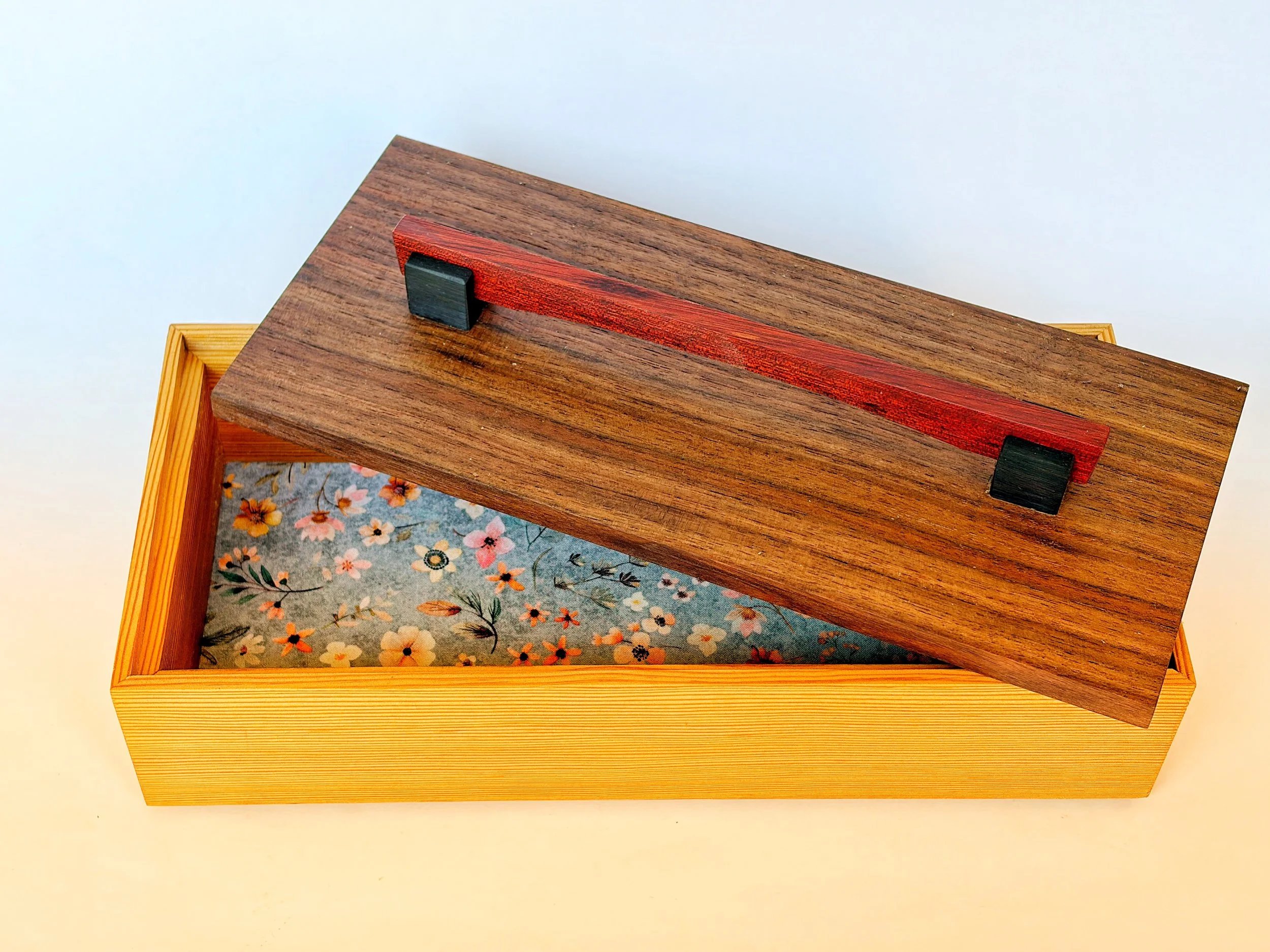 A wooden box with a floral patterned interior, viewed from above.