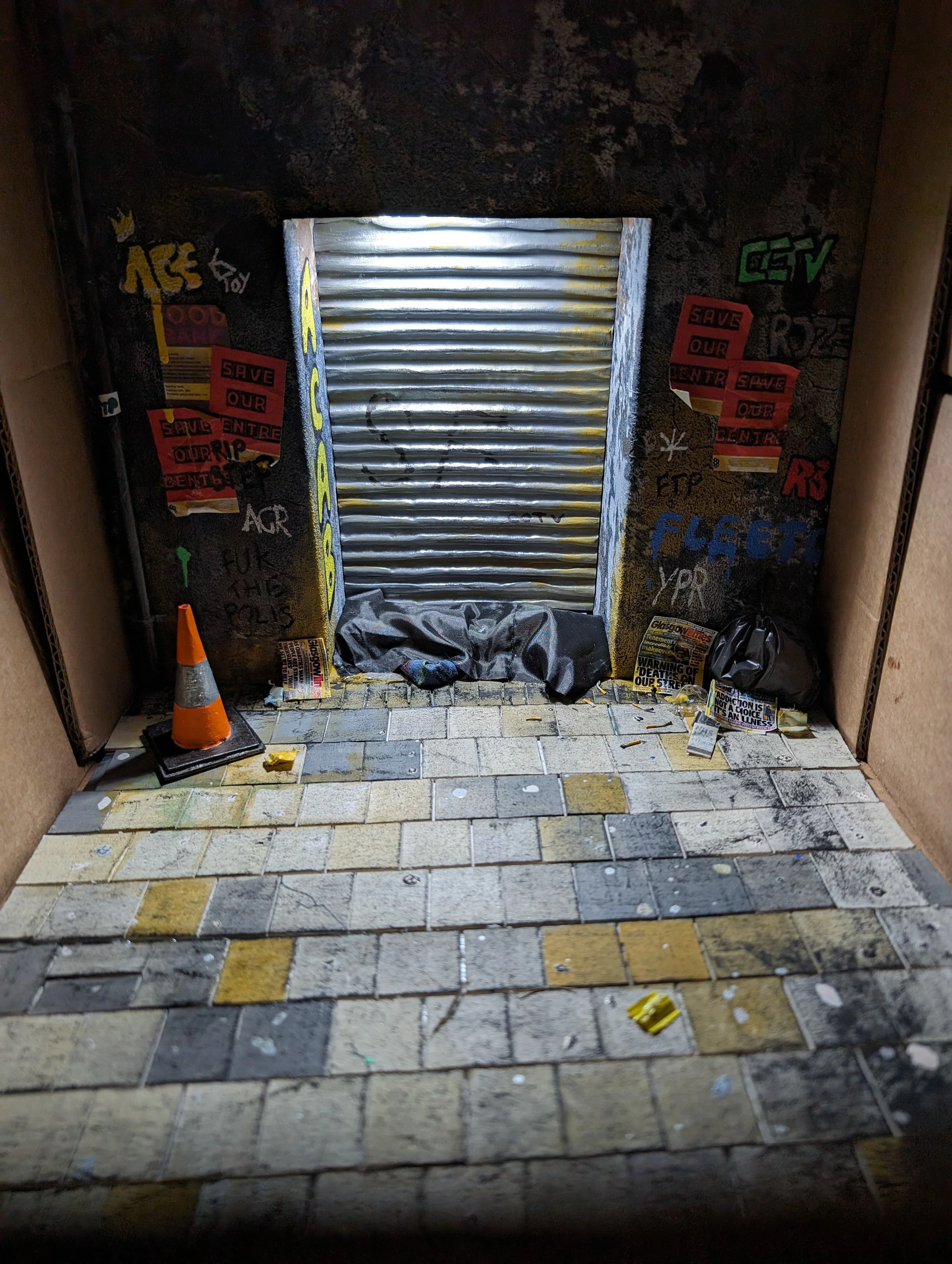 Diorama and protest piece on homelessness and the housing crisis of Glasgow, Scotland. The abandoned community services and centers are reflected in this piece.