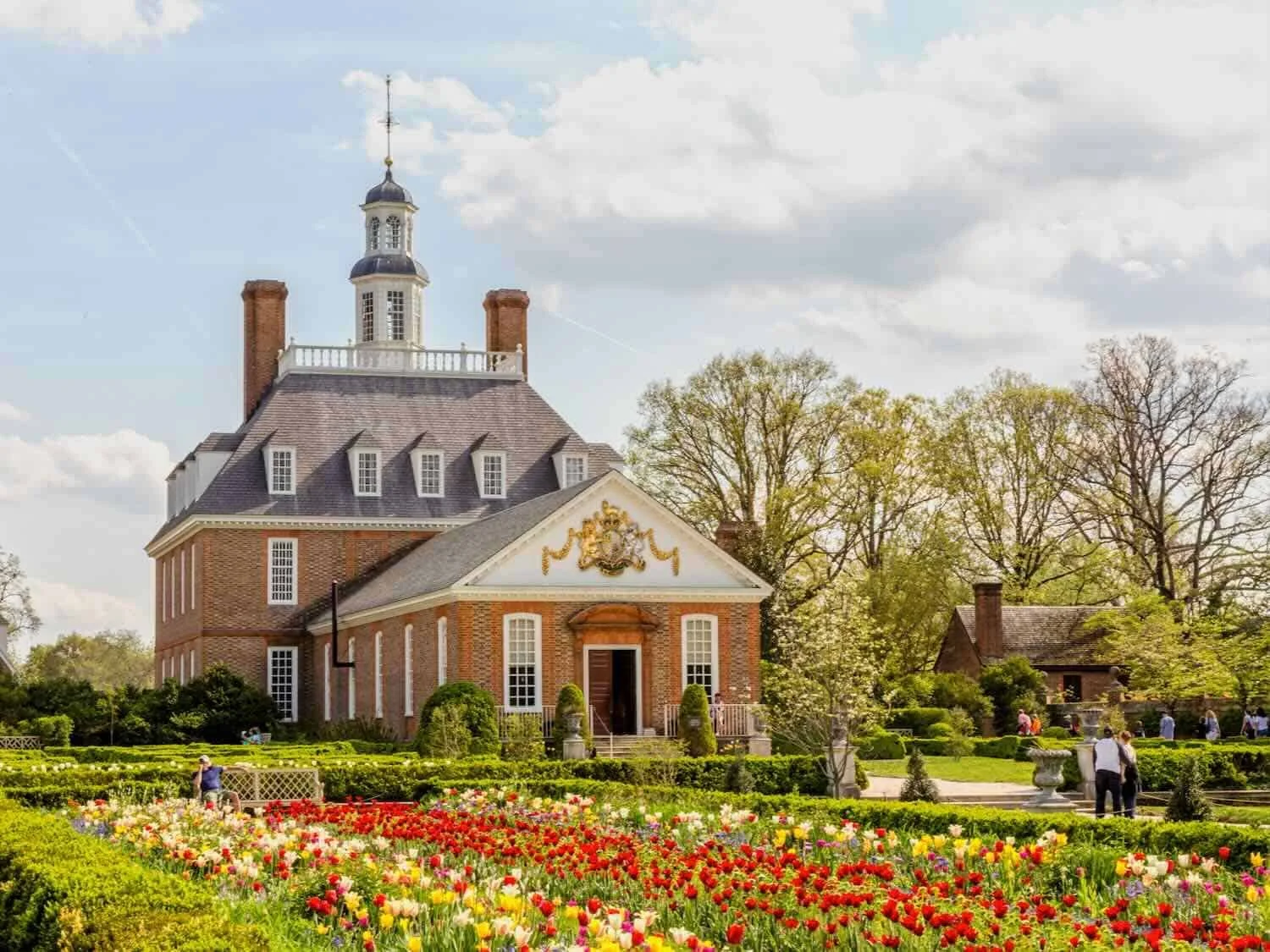 Historic brick building with a cupola and ornate facade surrounded by colorful tulip gardens