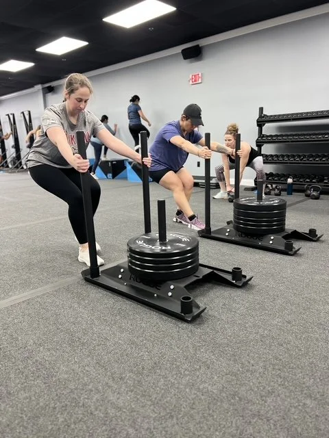 People using sled push equipment at gym with weight plates on sleds