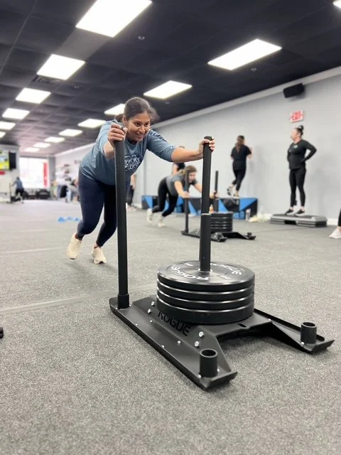 Woman pushing a weighted sled at the gym.