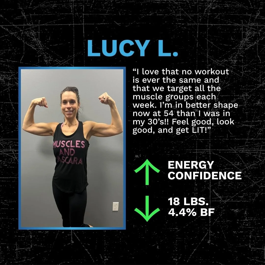 Photo of a woman flexing her arms, smiling, wearing a black tank top with pink text, standing against a plain gray wall.