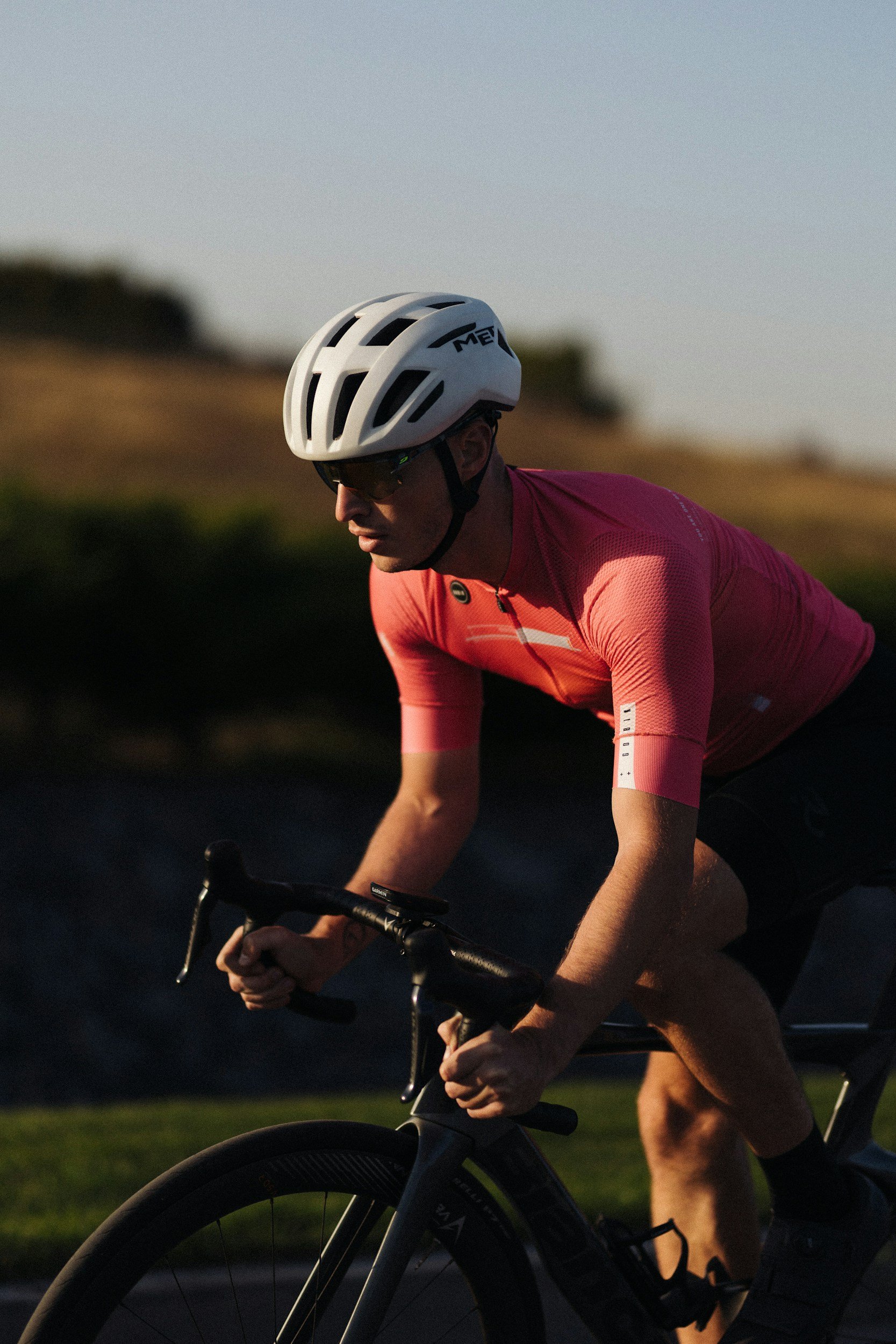 Male competitive cyclist outside in a red shirt and white helmet