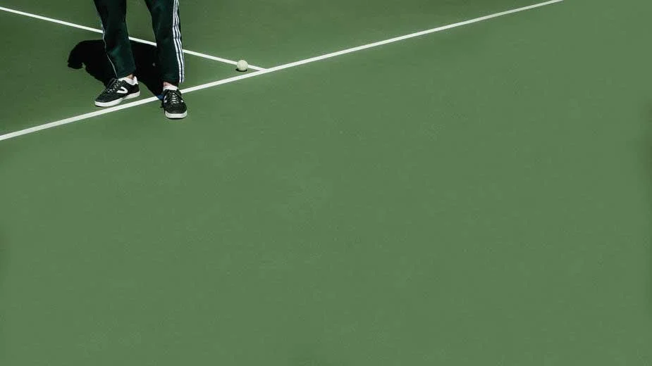 Cropped view of man in running shoes on a green tennis court