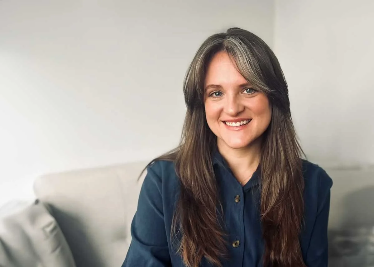 Therapist Maggie Stein Jamieson in a blue button up on a grey couch