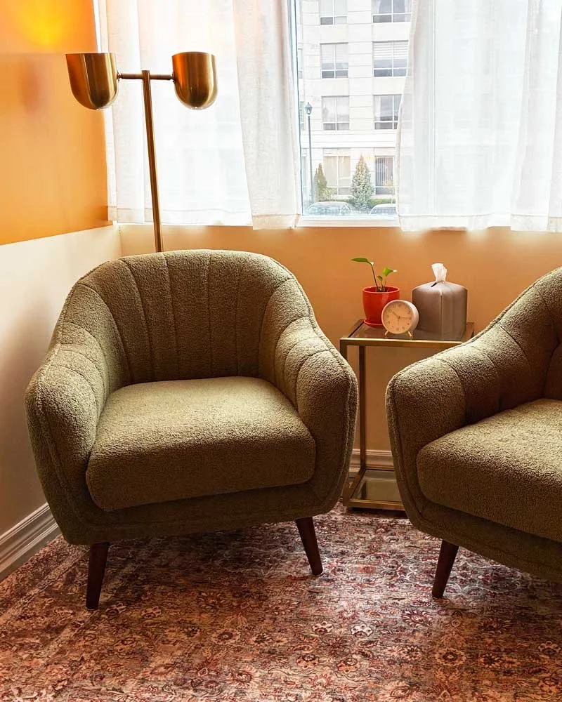 Two comfortsble green chairs in a bright peach room