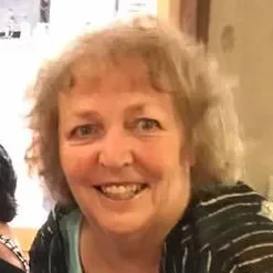 A woman with curly, light-colored hair smiling at the camera.