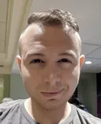 Close-up of a young man with short hair and fair skin taking a selfie indoors.