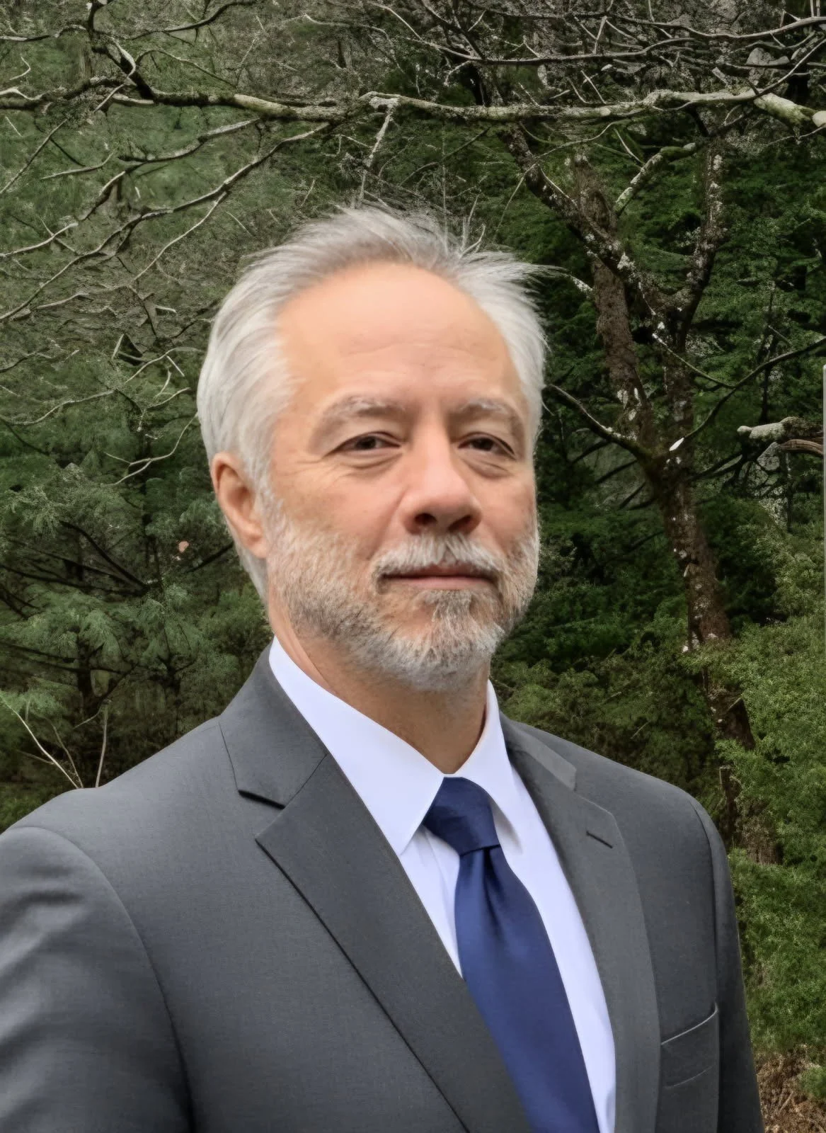 A smiling man in a suit and tie with short hair, no facial hair, and a light complexion.
