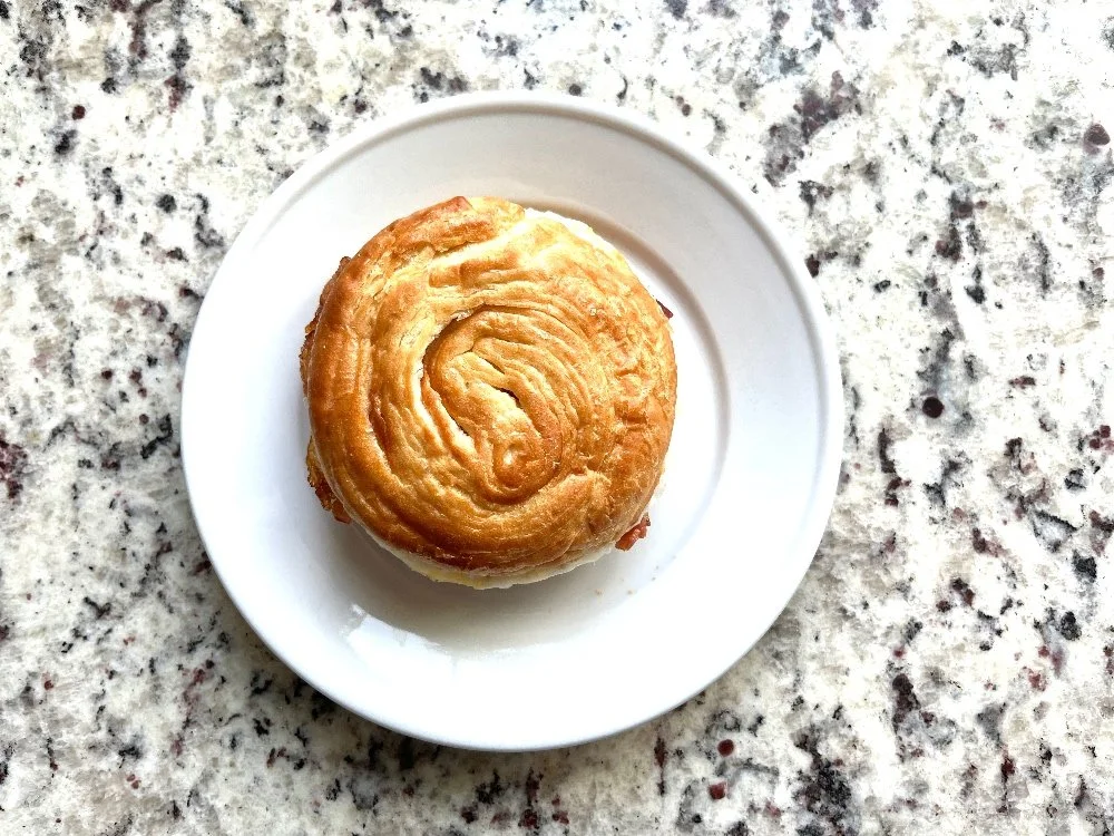 Costco breakfast sandwich on a white plate against a granite background