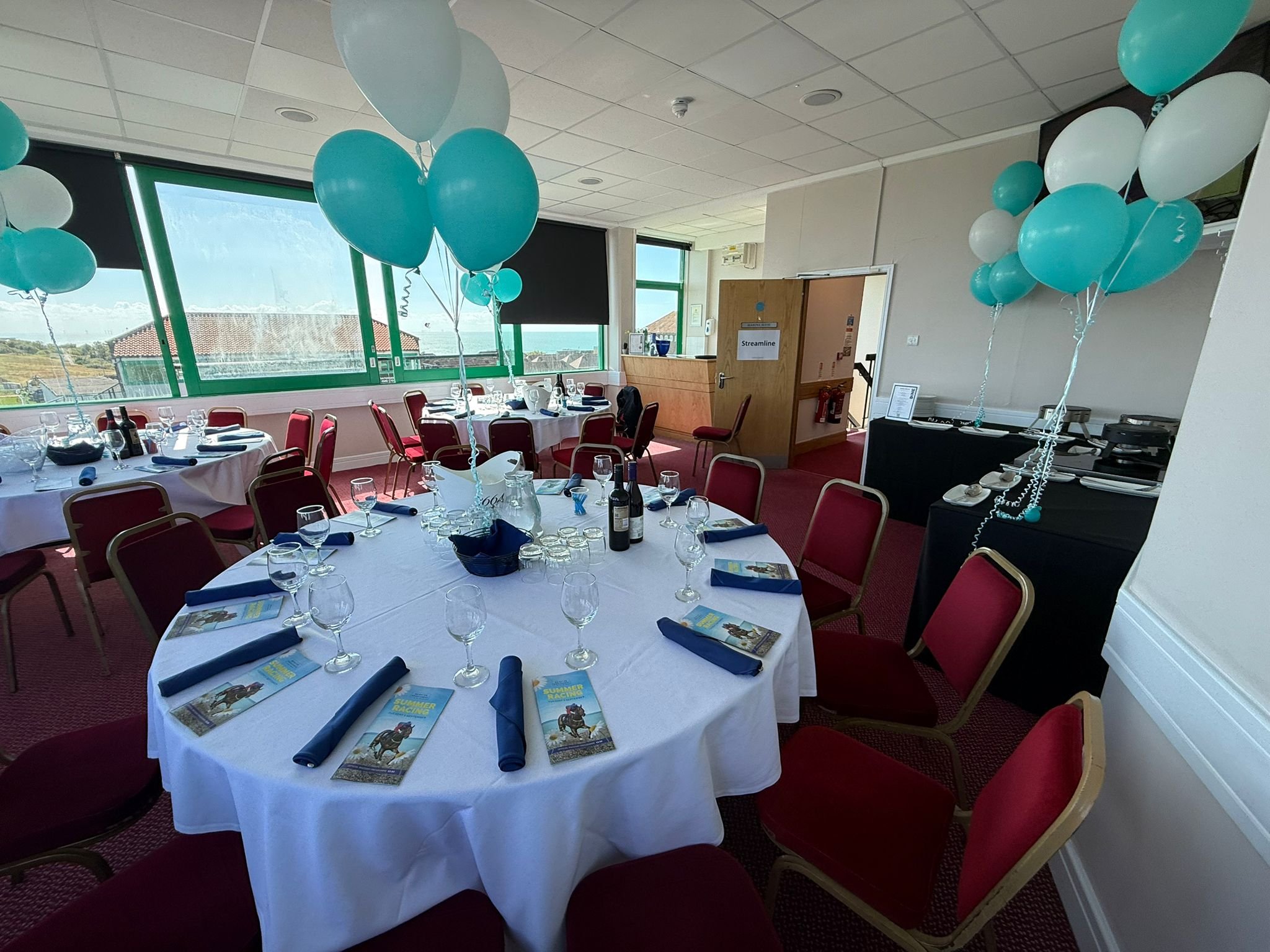 Function room set up with tables, balloons and catering for Streamline Taxis' Martlets Hospice evening at Brighton Racecourse