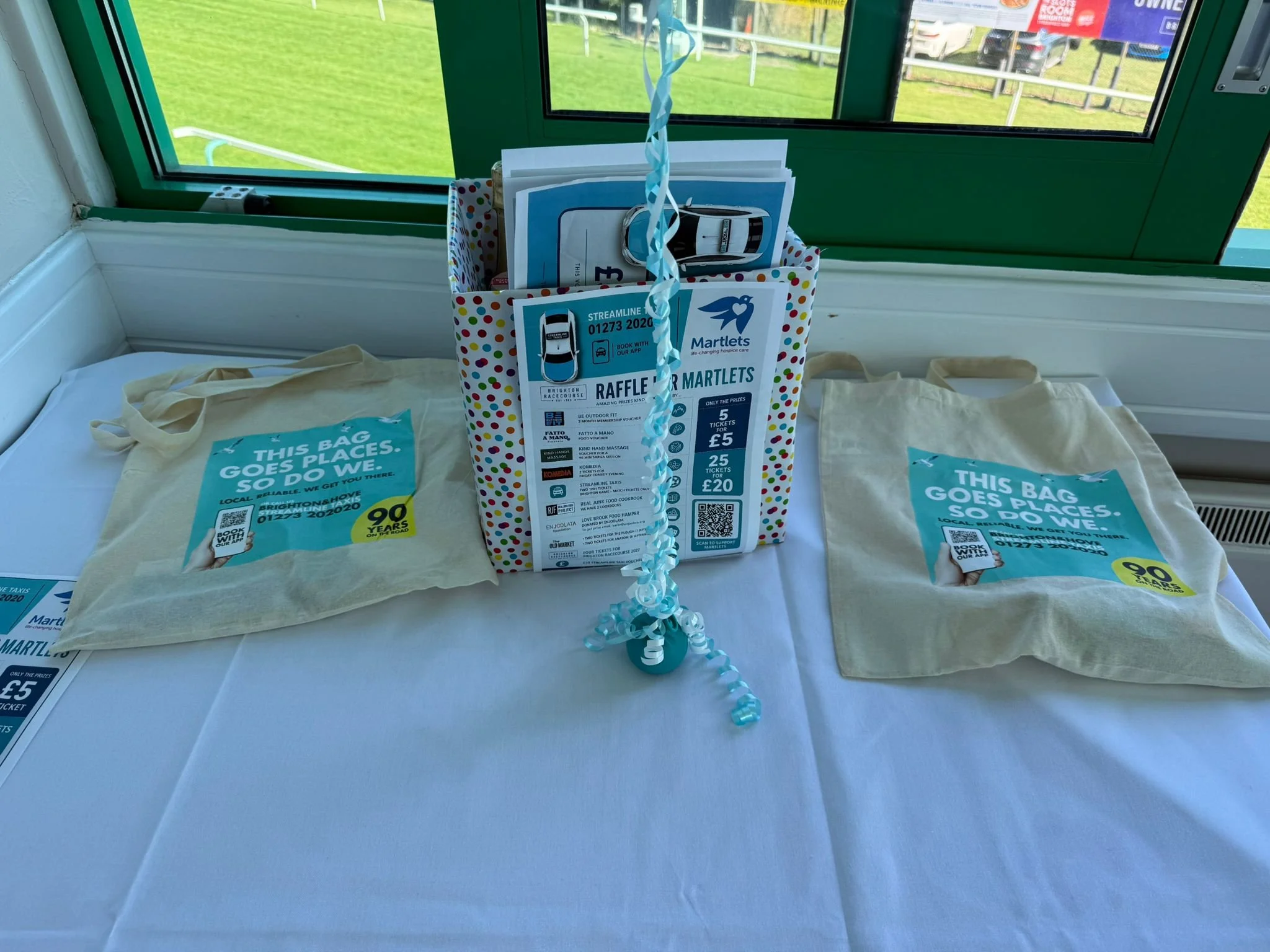 Raffle prize box flanked by Streamline Taxis 90 years tote bags at the Martlets Hospice evening
