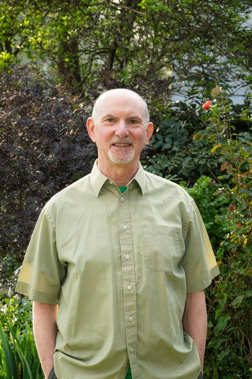 Mark Strong, Green Party councillor elected for Queen's Park in Brighton, smiling in a garden wearing a sage green shirt
