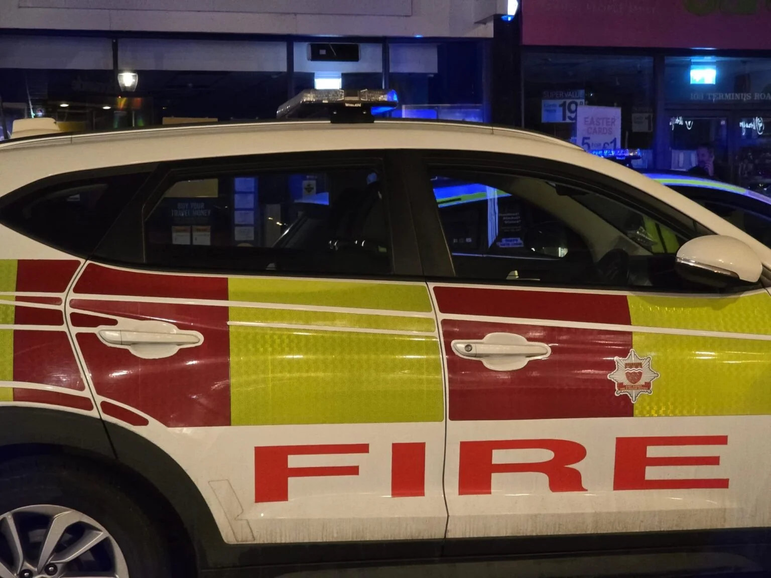 A Sussex fire and rescue vehicle parked at night outside shops on a Brighton street