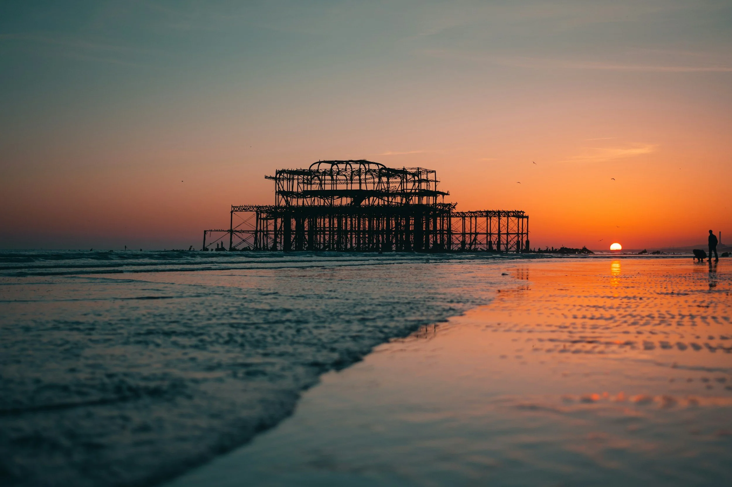 The abandoned West Pier in Brighton during sunset with reflections across the seafront.