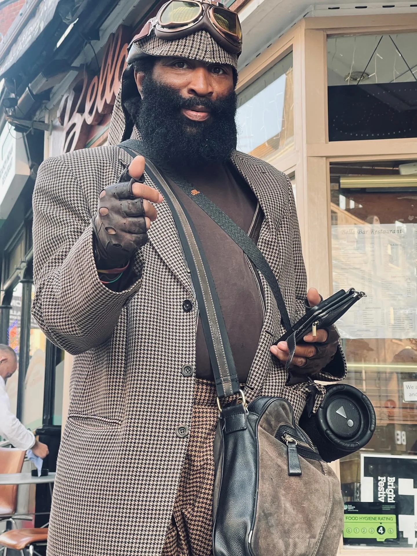 Charles Pirate Saddler in a houndstooth suit and goggles with his speaker on a Brighton street