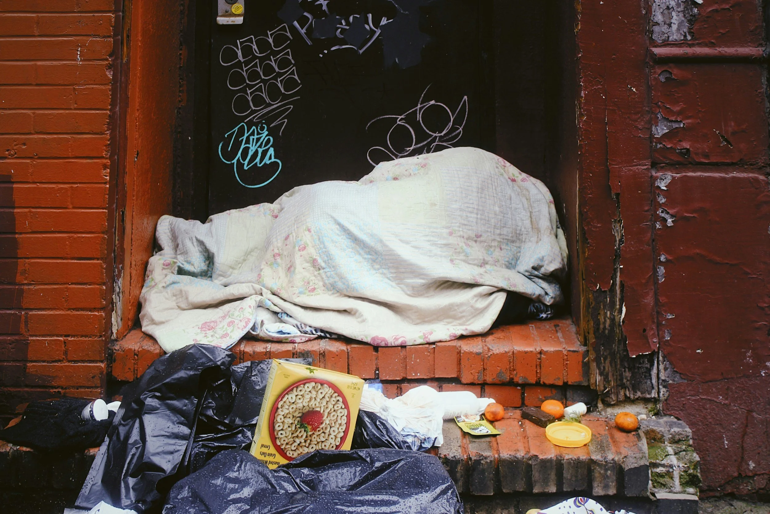 Bedding, food and belongings left in a doorway representing street homelessness and the urgent need for temporary accommodation support