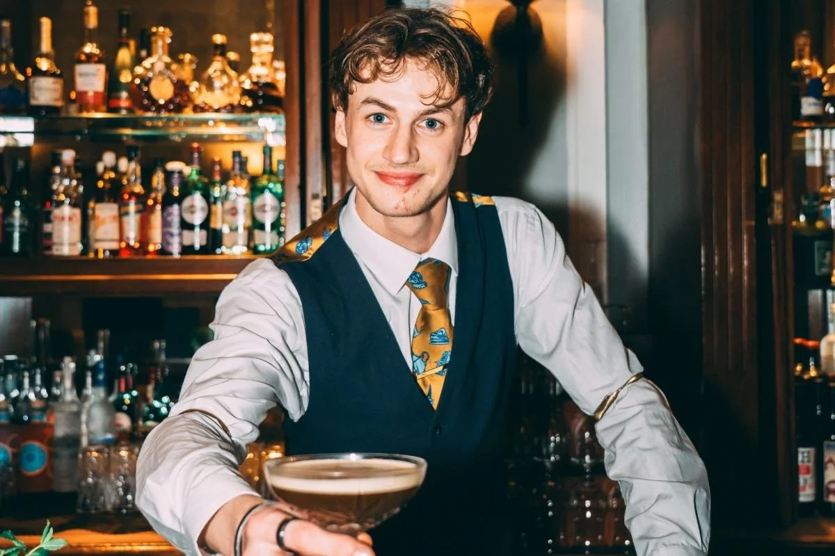 A Brighton bartender in a waistcoat and tie presenting an espresso martini cocktail