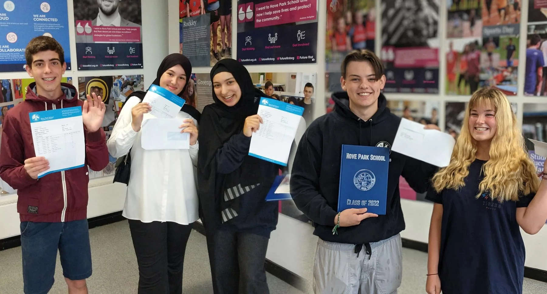 Five Hove Park School pupils smiling and holding their results slips inside the school