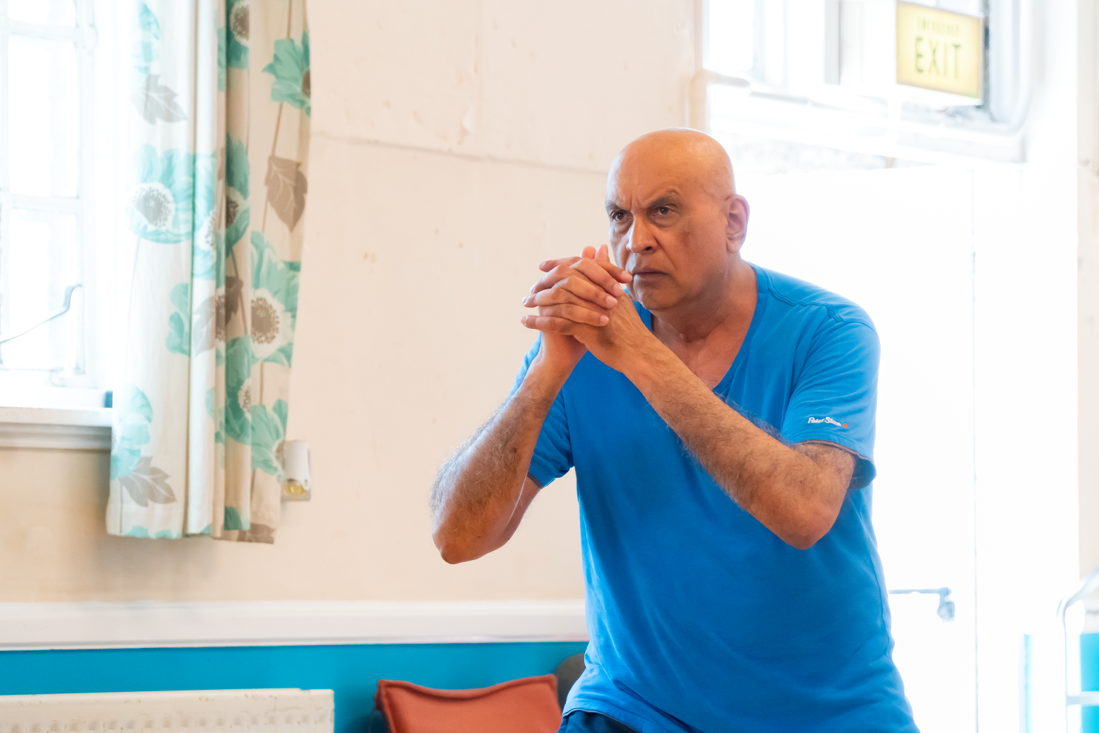 Brighton and Hove resident Eugene with his hands clasped in front of him during an exercise class in a community hall