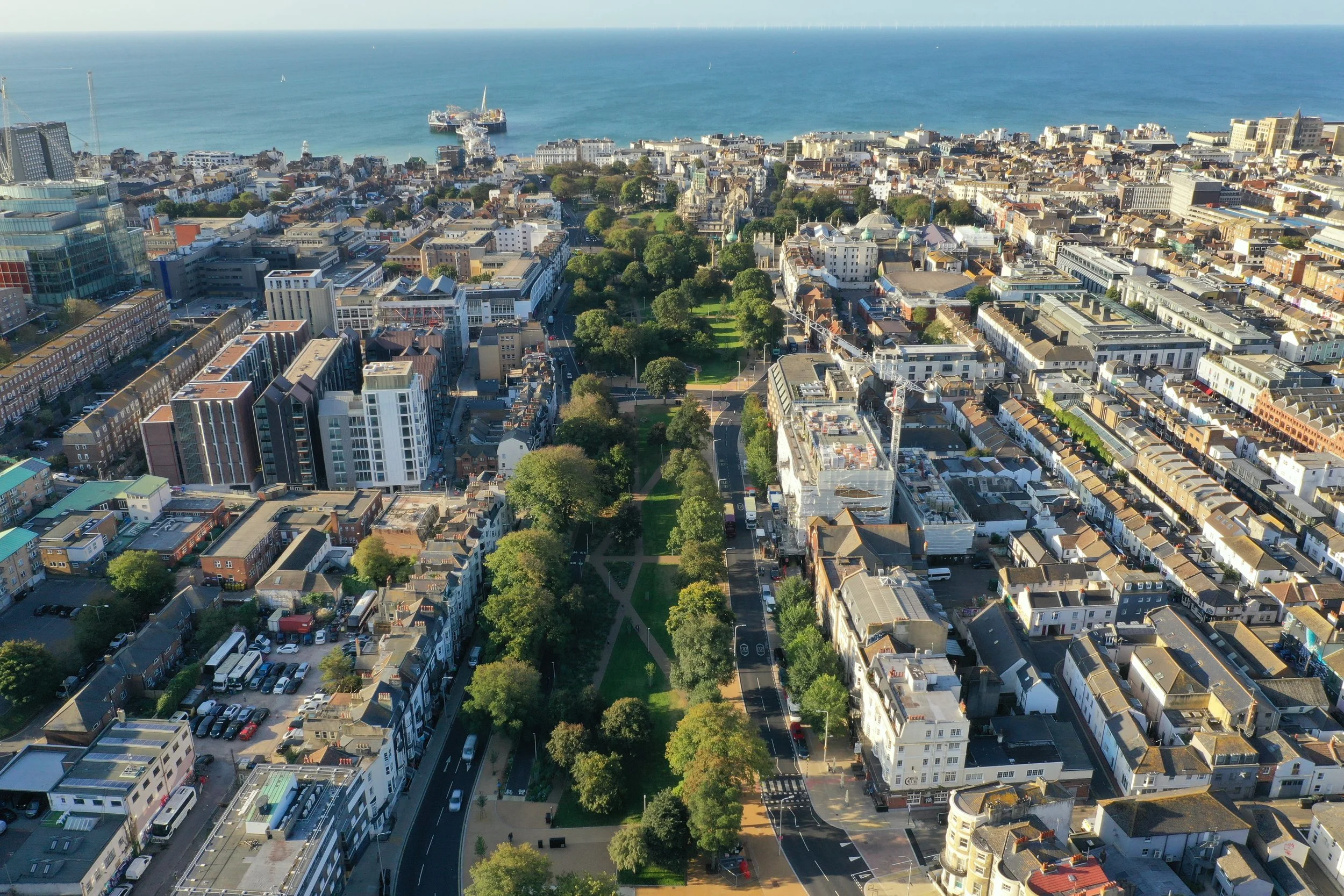 Aerial view over Brighton and Hove rooftops, parks and seafront, with the City Plan logo