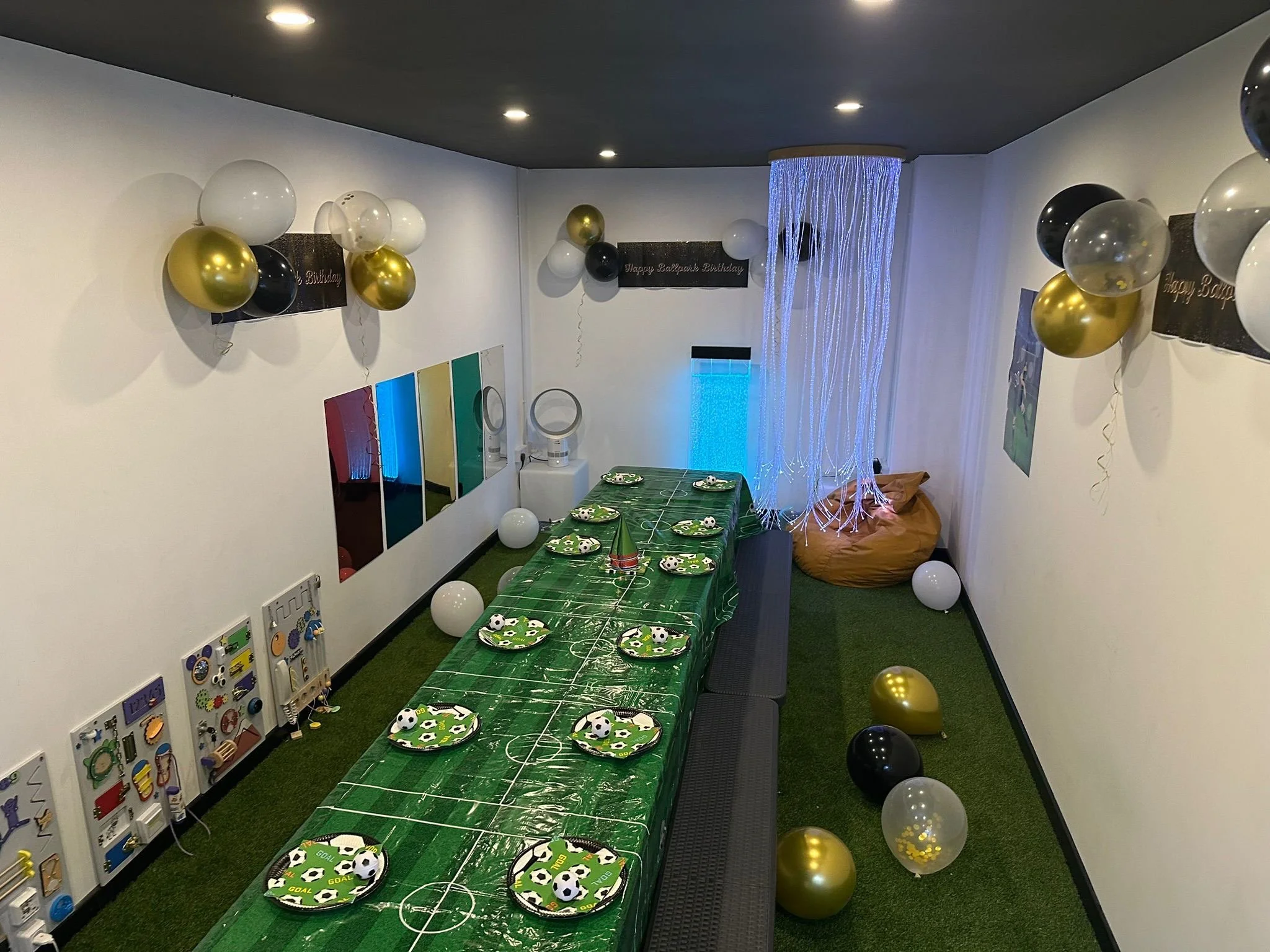 A birthday party room at Ball Park Brighton Marina with a football tablecloth, balloons and a fibre optic light curtain