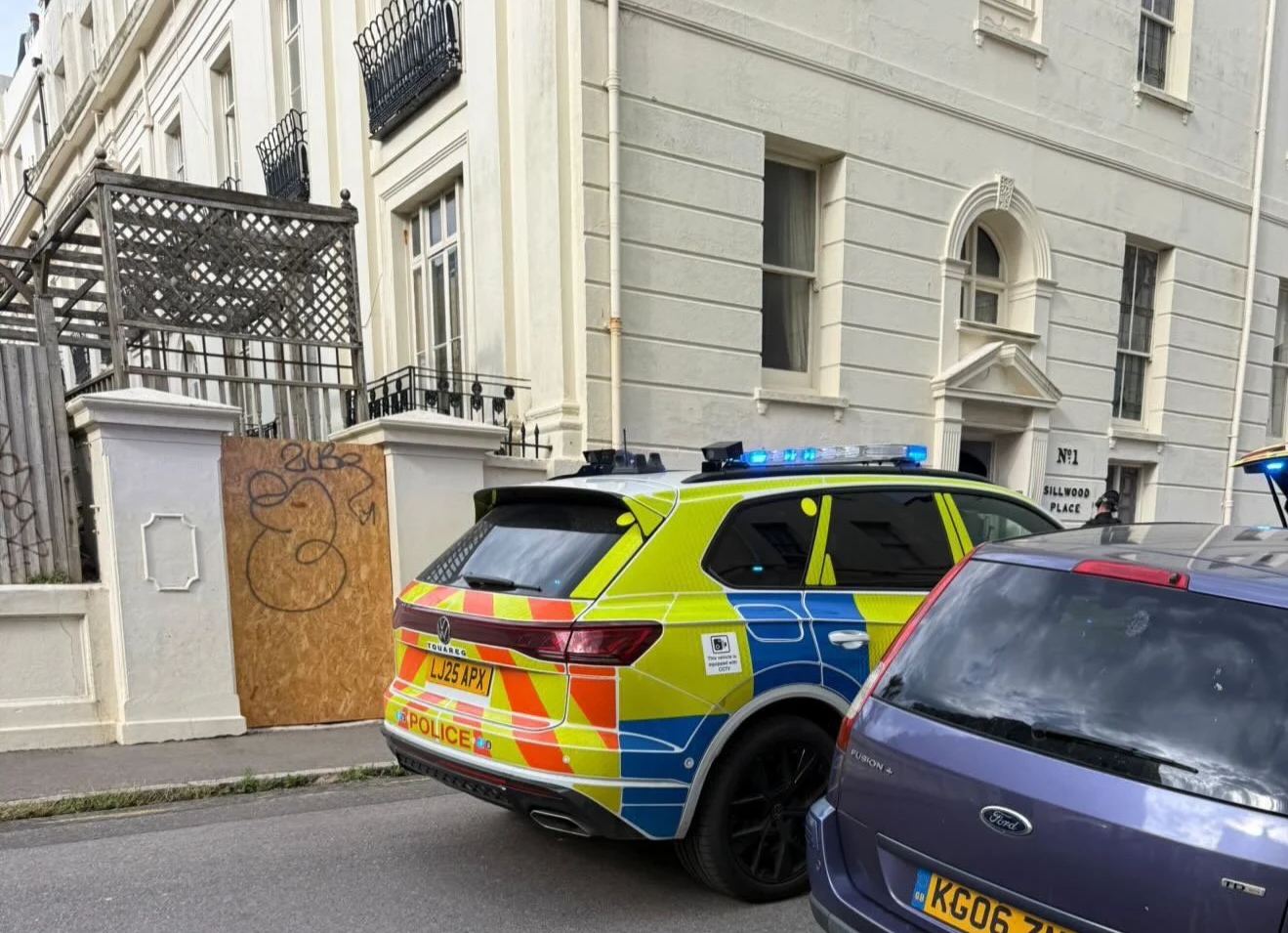 A Sussex Police car with blue lights outside a building on Sillwood Street in Brighton